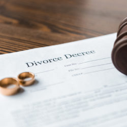 What to expect at your first consultation with a divorce lawyer - marriage contract, wedding bands, gavel, on table wood