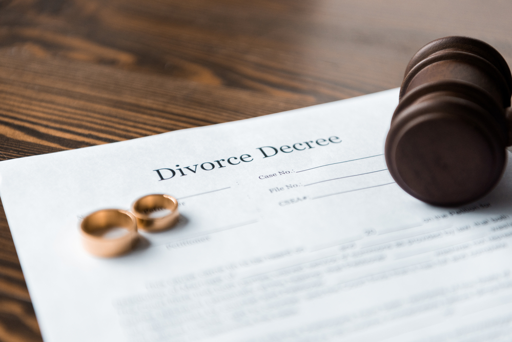 What to expect at your first consultation with a divorce lawyer - marriage contract, wedding bands, gavel, on table wood