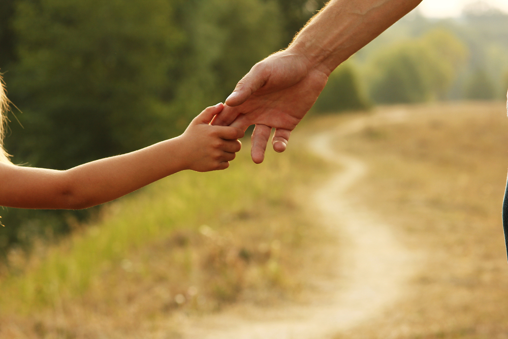 Helpful Co-Parenting Tips for the Summer - parent holds the hand of a small child